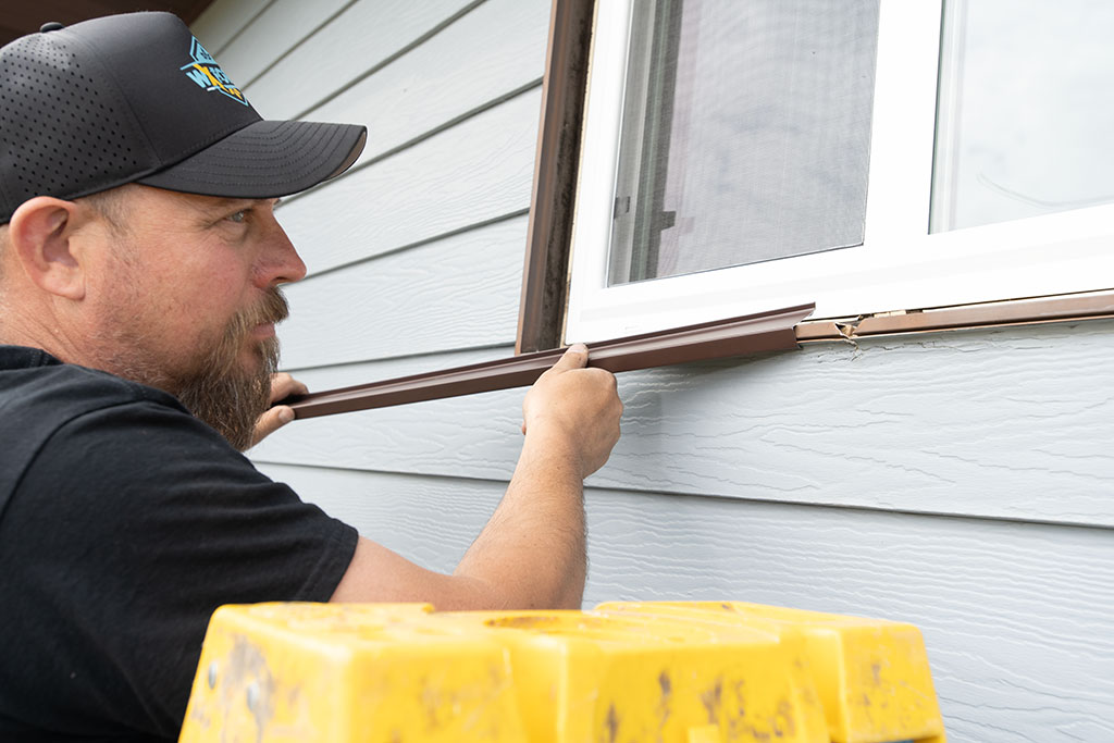 a WxForce crew member installing weather stripping on the exterior side of a window on a home