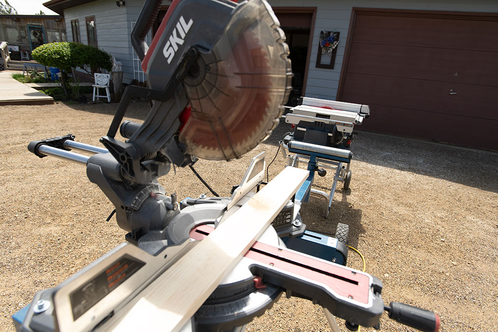 a table saw set up in the driveway of a home that is being worked on